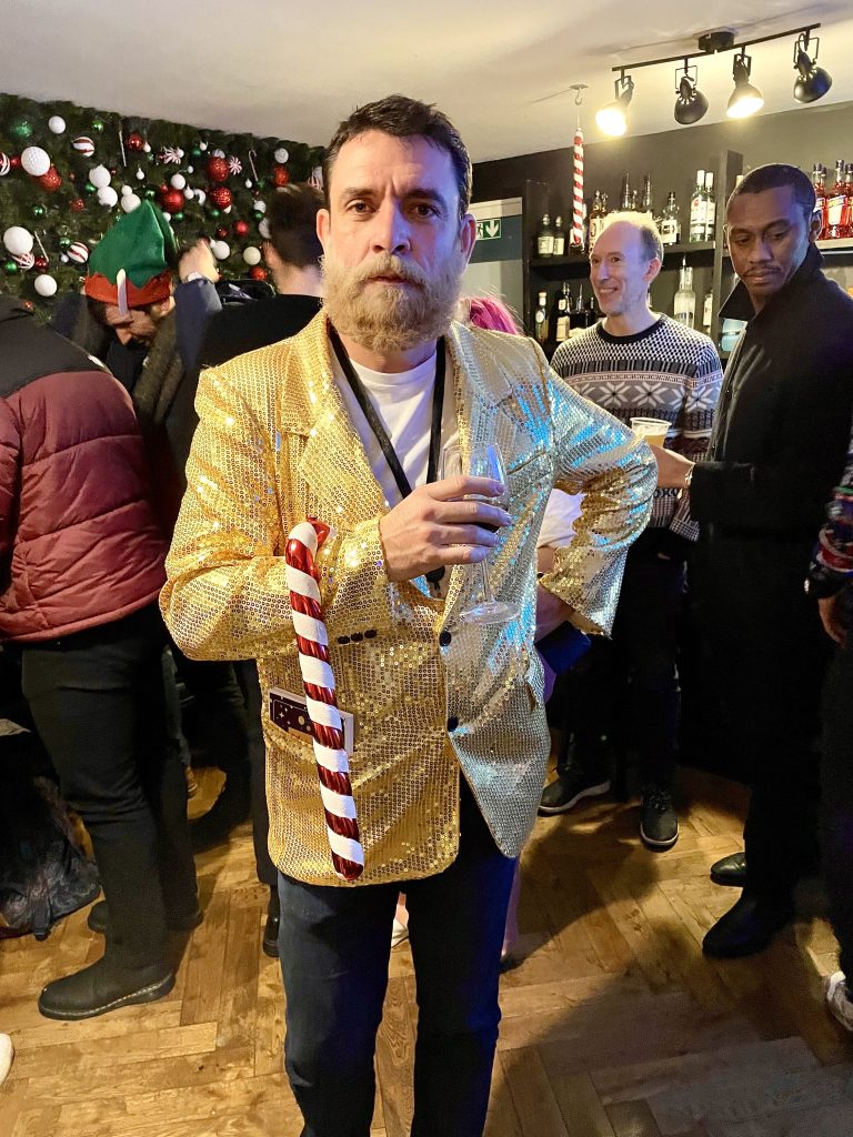 Mark in his gold jacket and white beard posing as santa clause